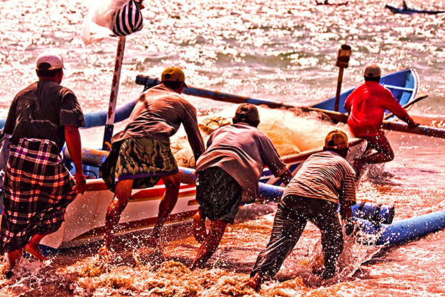 El espíritu de cooperación (gotong royong), playa de Jimbaran, en Bali, Indonesia. (cc) novriwahyuperdana Pescadores de Bali empujando un bote hacia el mar
