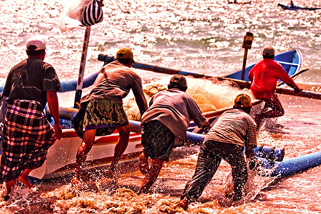 Pescadores de Bali empujando un bote hacia el mar